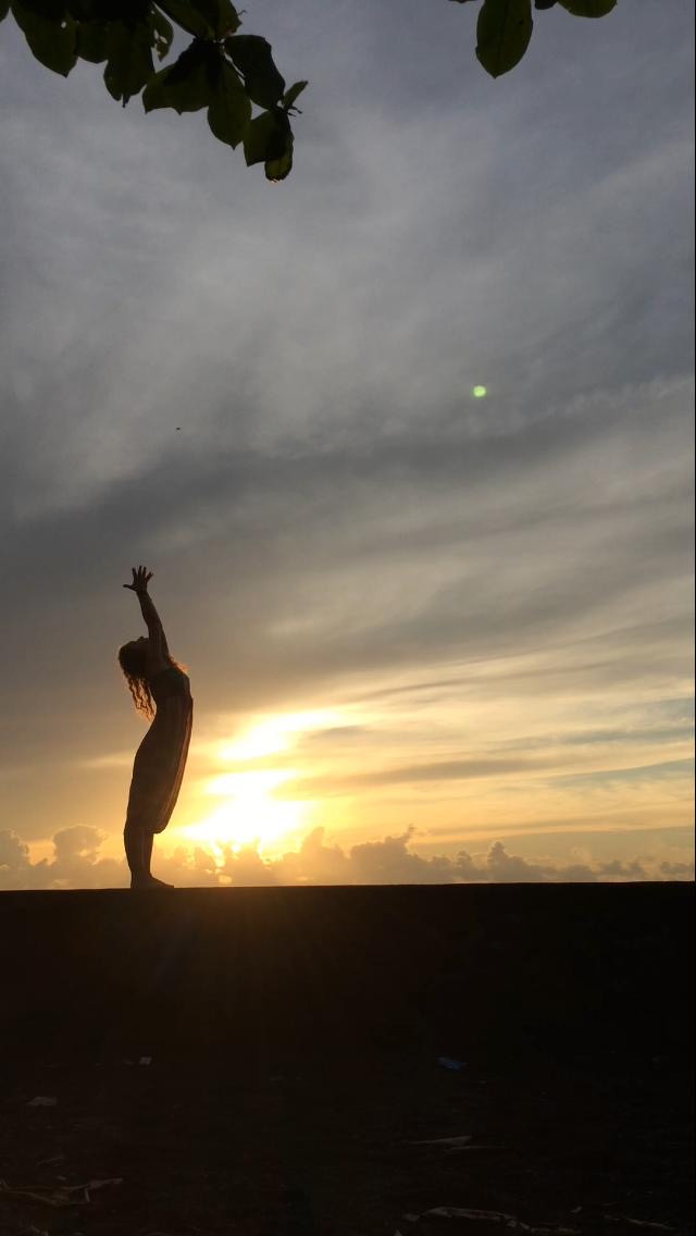 A silhouetted figure with arms raised against a golden sunset.